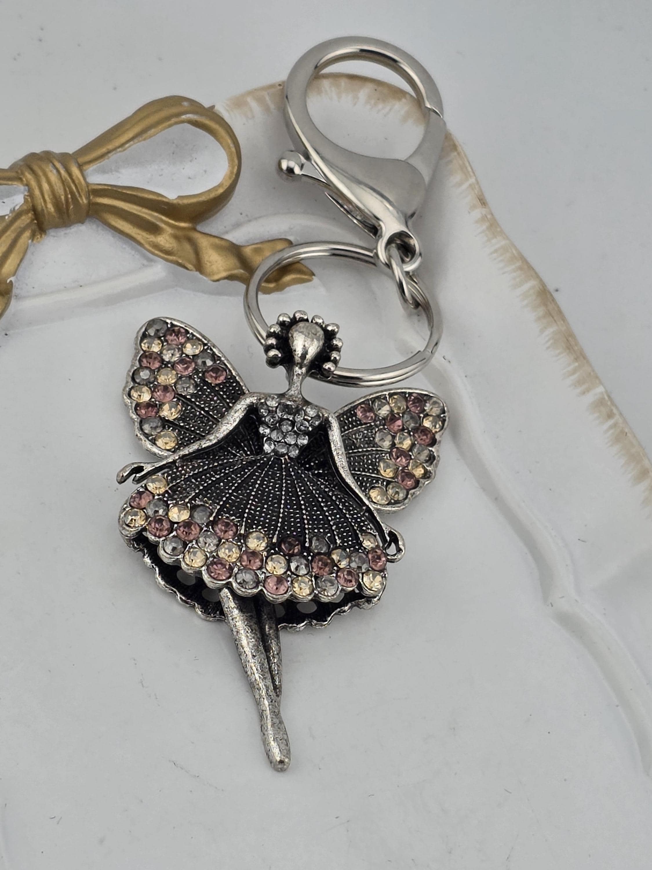 A silver-colored keychain with a decorative butterfly design and sparkling gemstones.