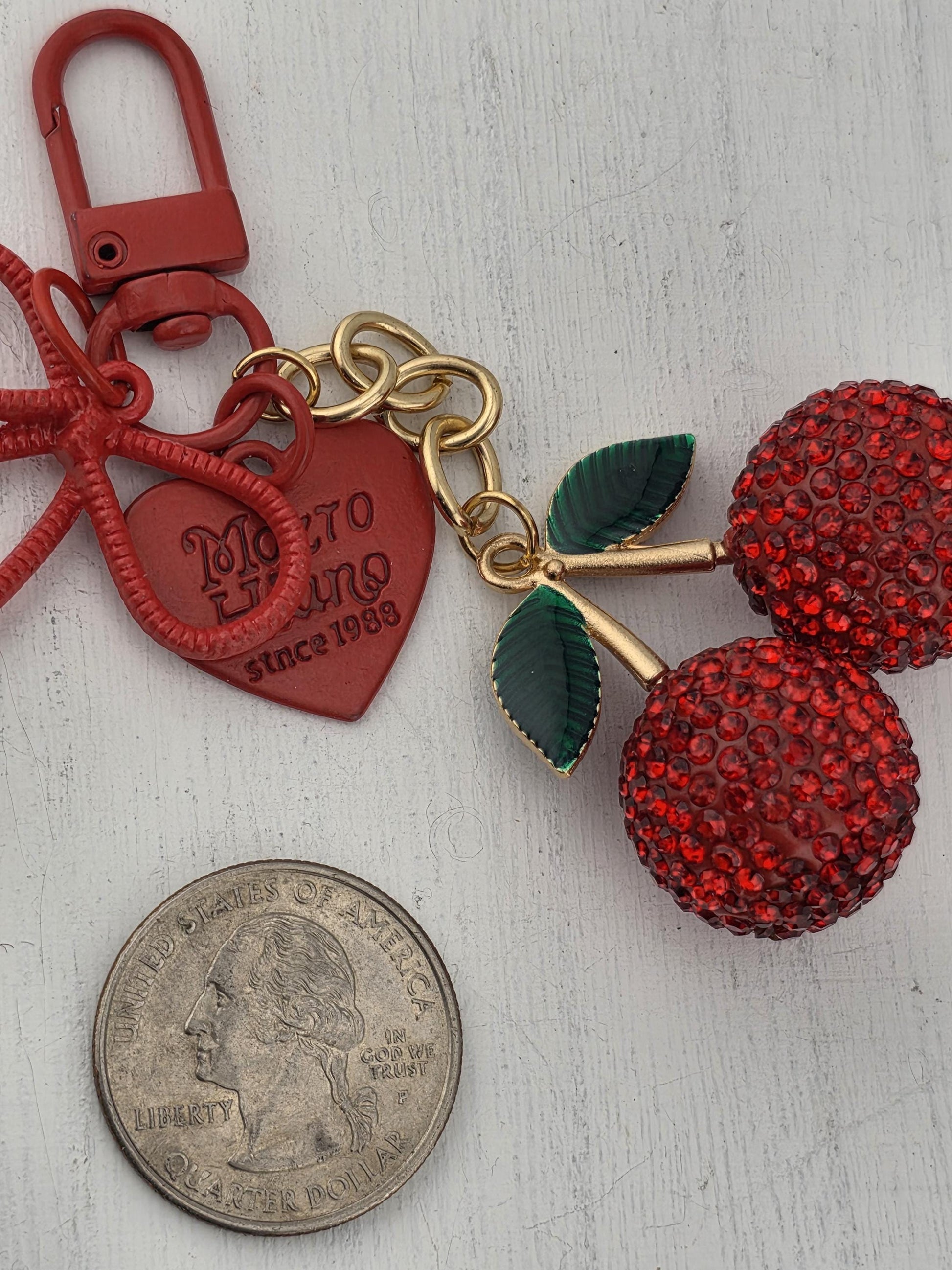 a keychain with a red heart-shaped charm and a small coin placed next to it on a white surface.
