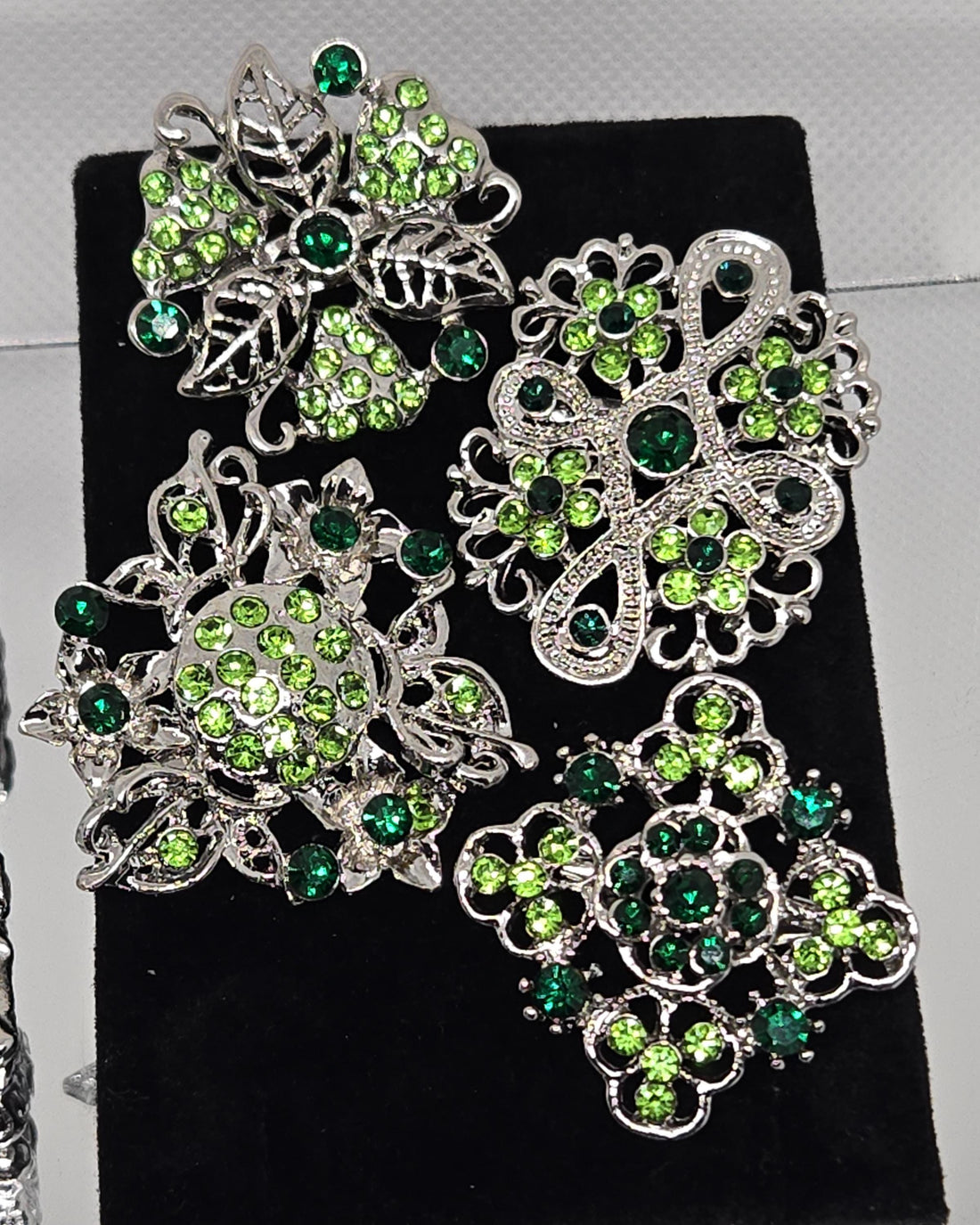 a collection of ornate brooches adorned with green gemstones.