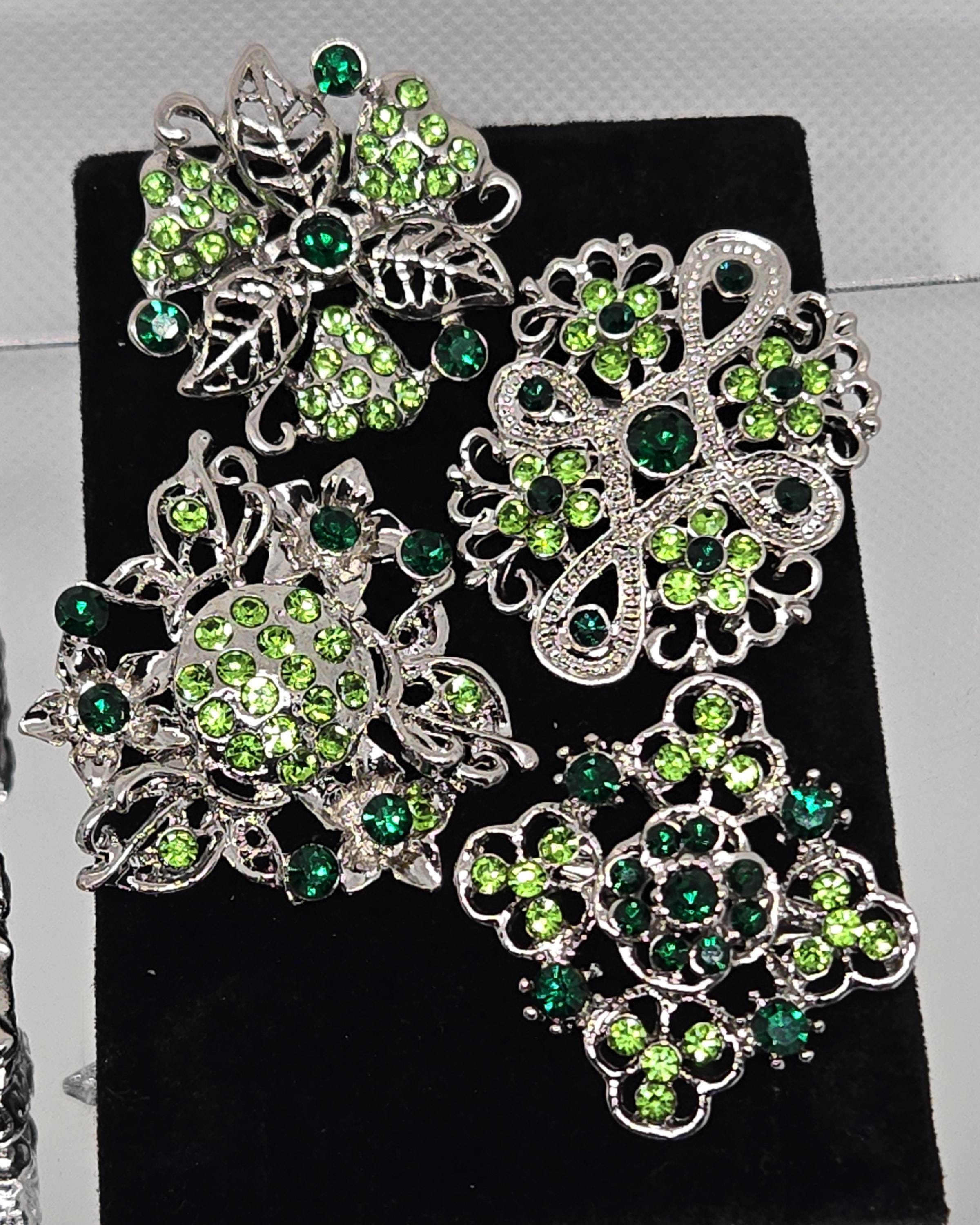 a collection of ornate brooches adorned with green gemstones.