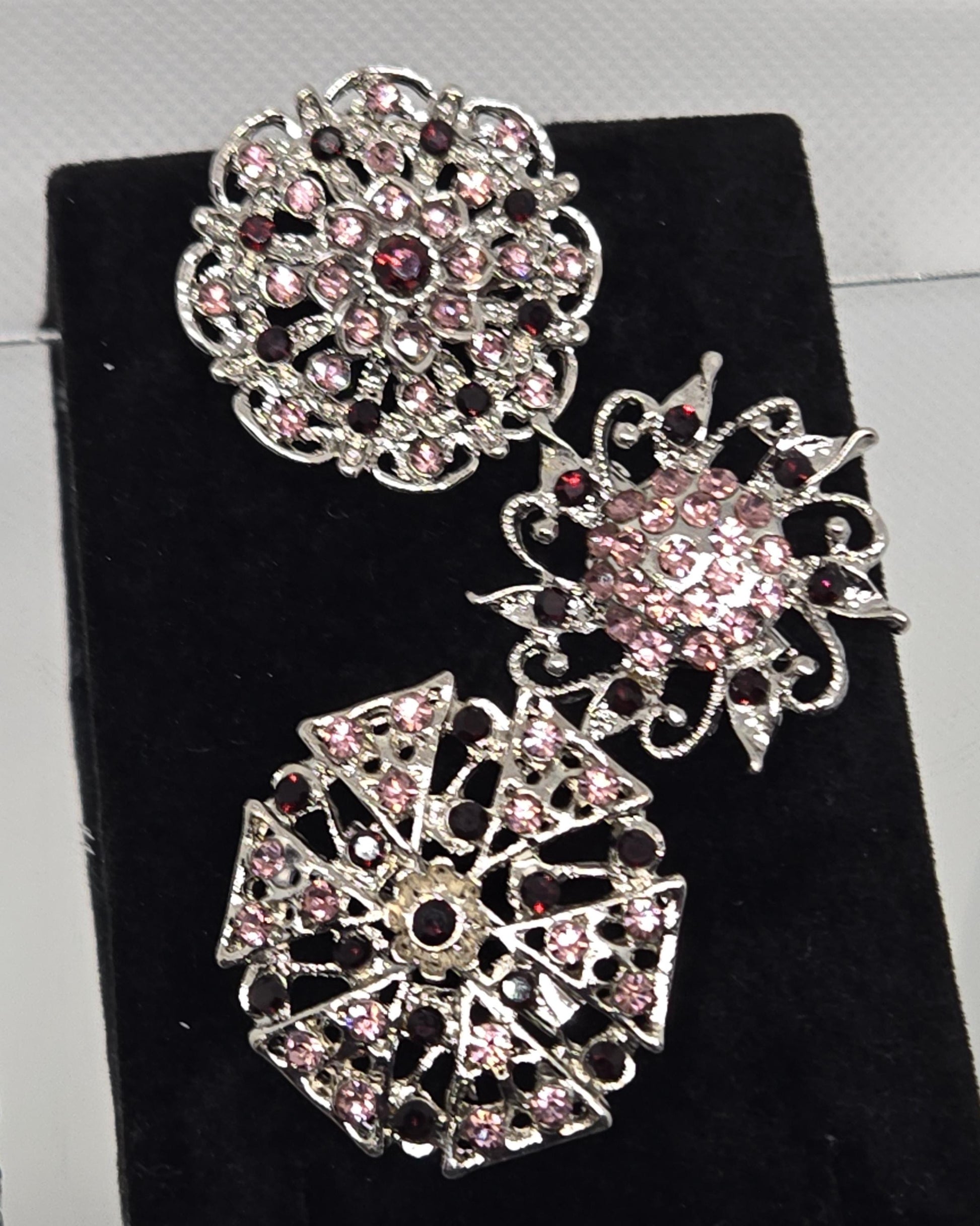three ornate brooches with intricate designs and sparkling gemstones.