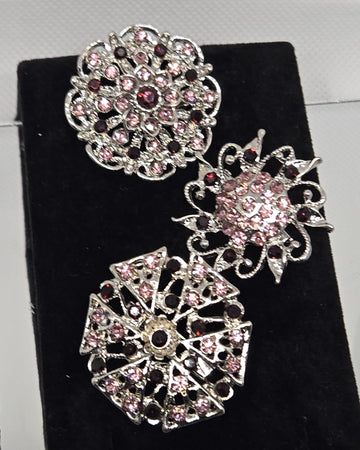 three ornate brooches with intricate designs and sparkling gemstones.