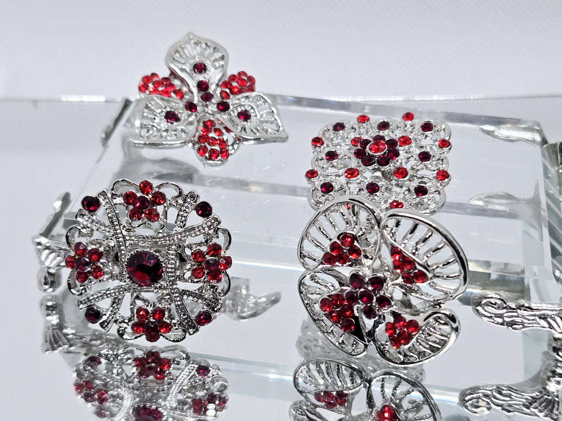 a collection of ornate brooches adorned with red gemstones, displayed on a black velvet background.