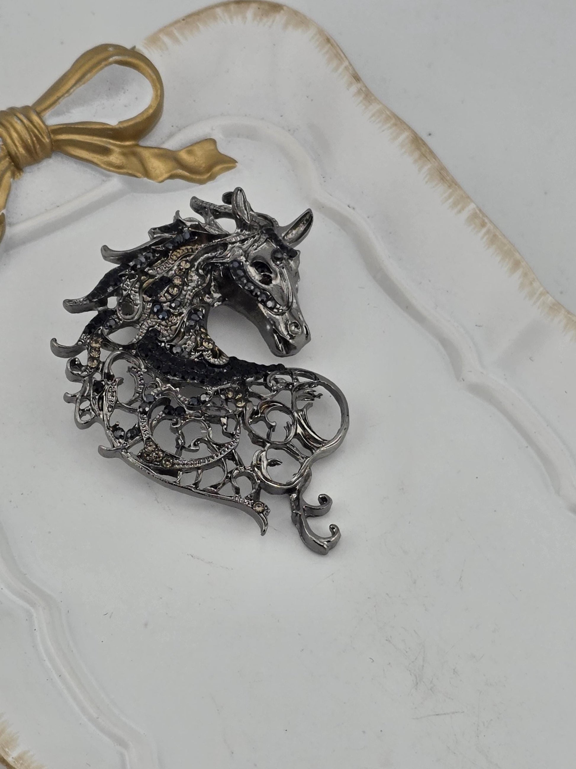 a decorative metal piece resembling a horse's head, which is placed on a white surface.