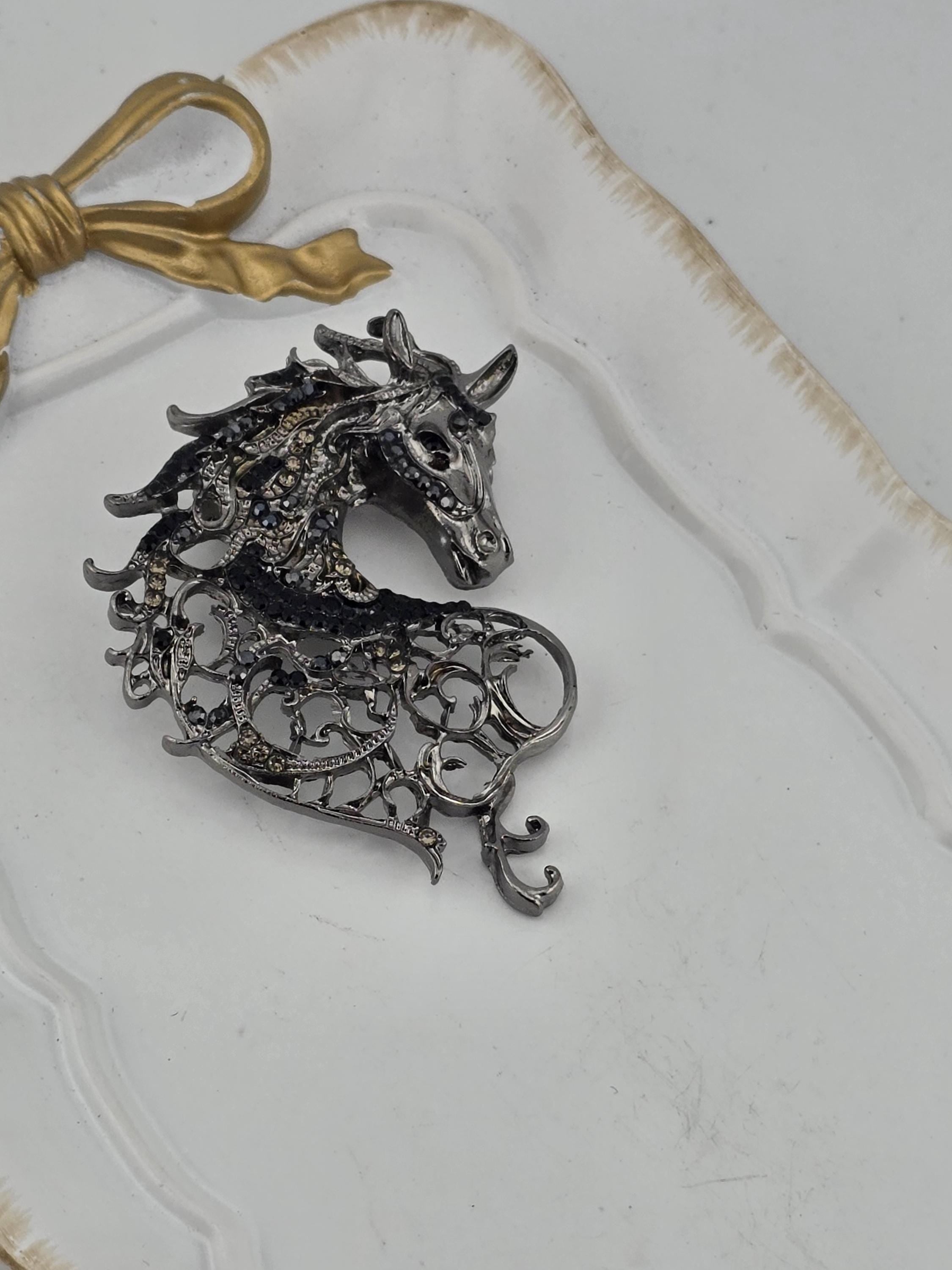 a decorative metal piece resembling a horse's head, which is placed on a white surface.