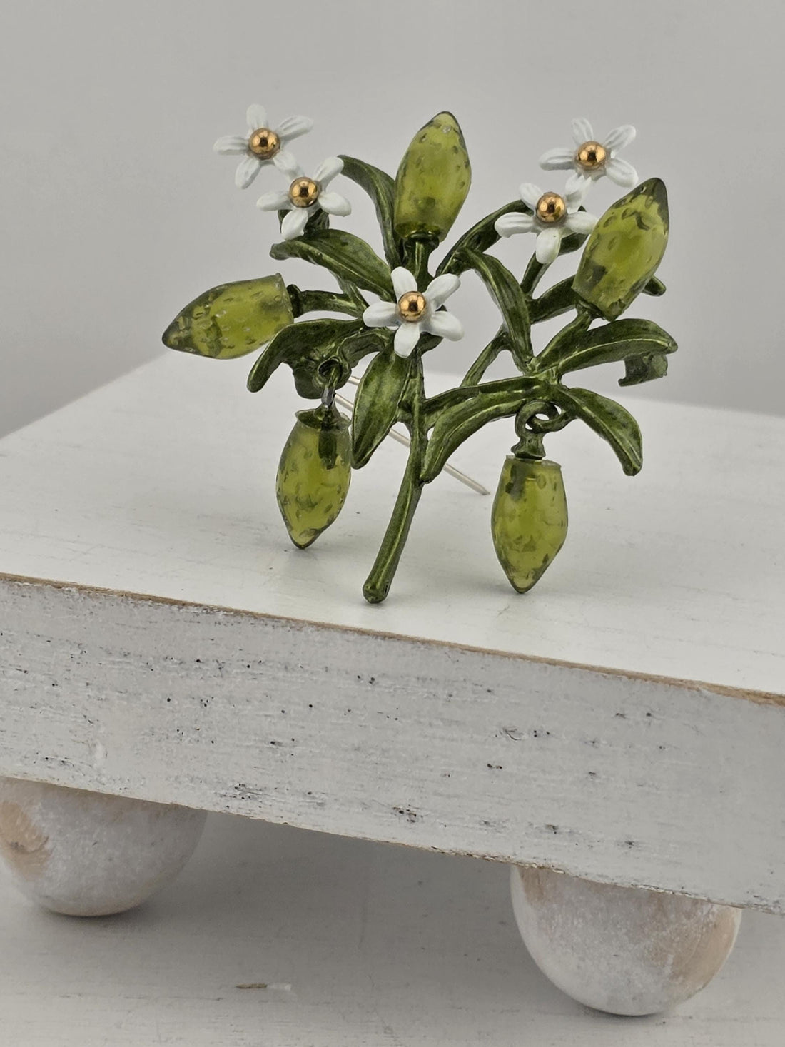A decorative green and white floral arrangement with small white flowers is displayed on a white surface.
