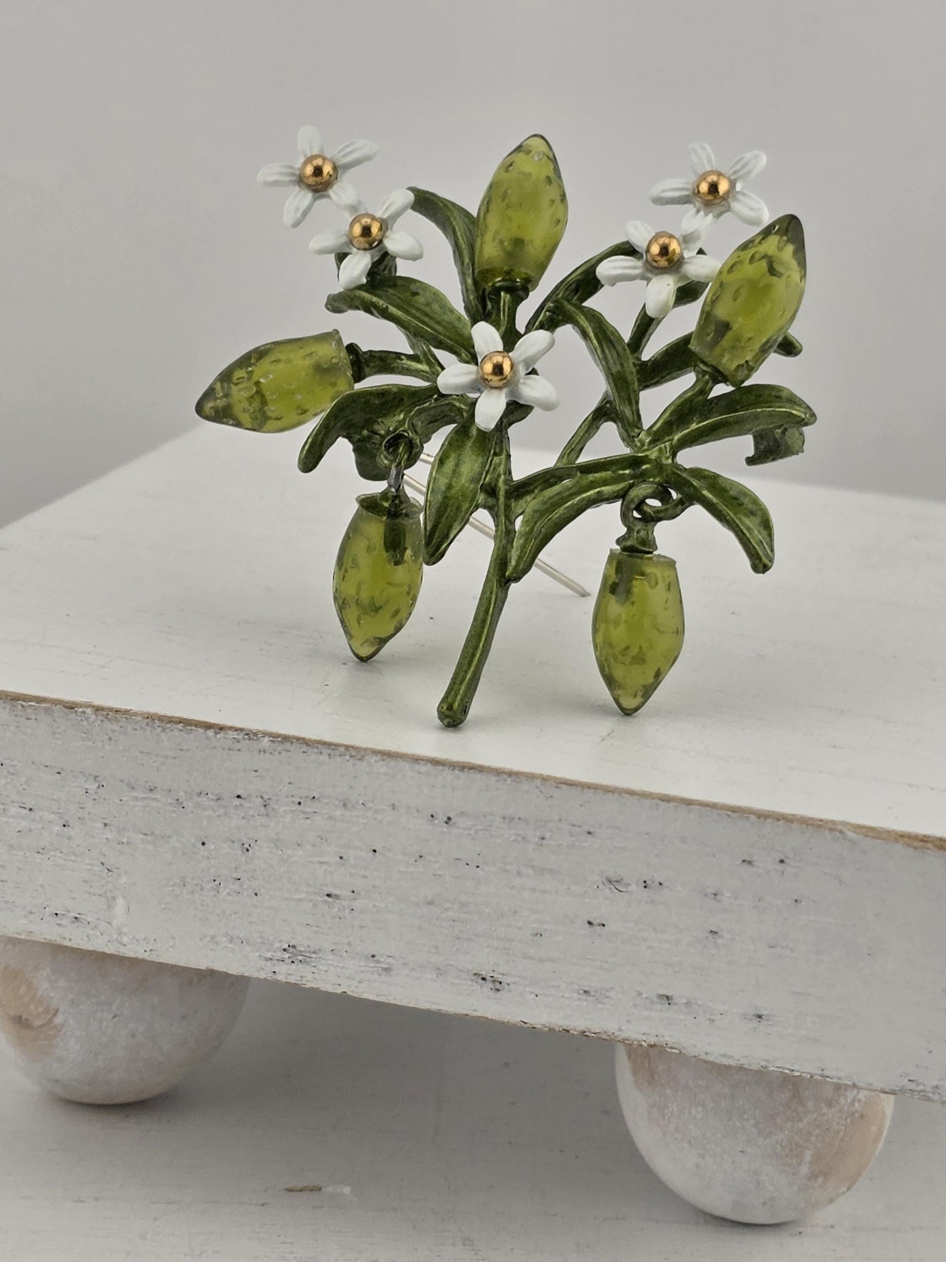 A decorative green and white floral arrangement with small white flowers is displayed on a white surface.