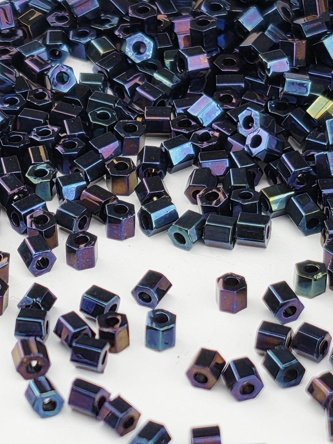 numerous small, metallic hexagonal objects in various shades of blue and purple, scattered across a white background.