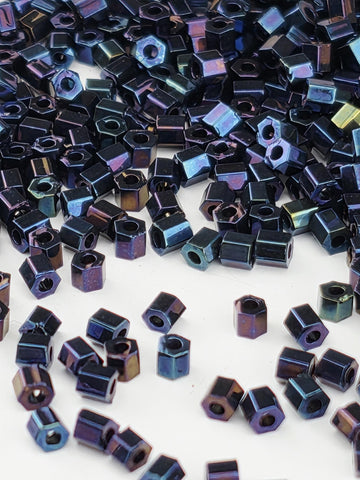 numerous small, metallic hexagonal objects in various shades of blue and purple, scattered across a white background.