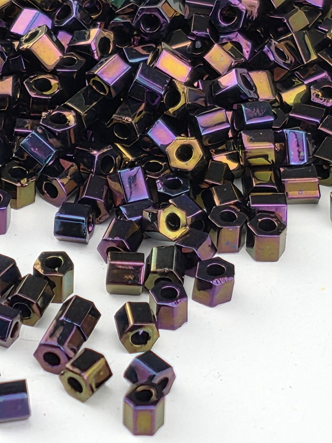 a collection of small, multicolored metal nuts or bolts scattered on a white background.