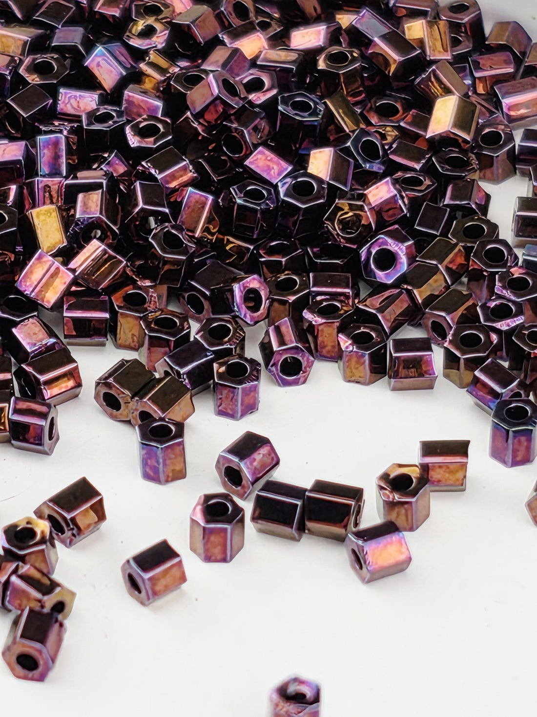 a close-up view of numerous small, square-shaped metal pieces in various shades of purple and brown, scattered across a white background.