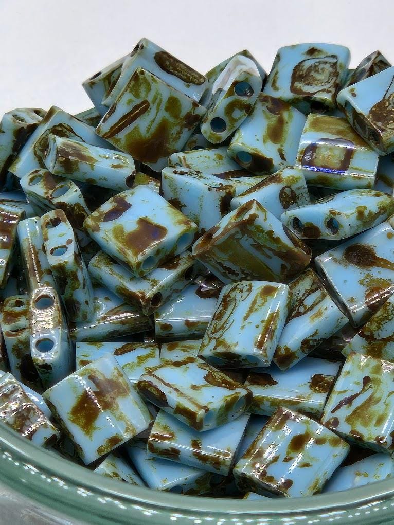a close-up view of a collection of blue and brown glass beads or stones, arranged in a bowl or container.