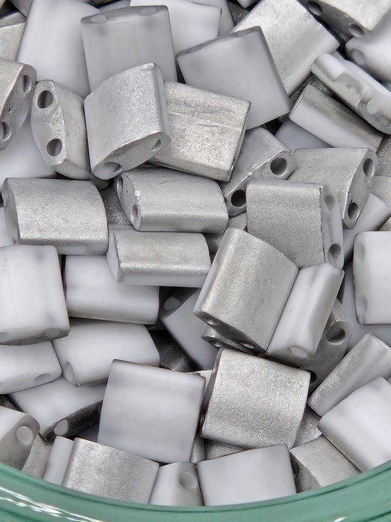 numerous small, metallic objects that appear to be made of silver or metallic material. They are arranged in a pile or a container, with some overlapping each other. The objects are not described in detail, and the image does not contain any text.