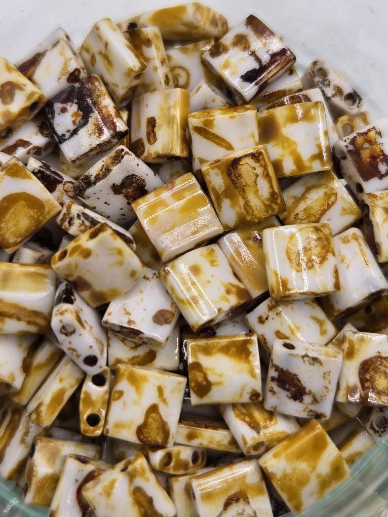 a close-up view of numerous small, square-shaped objects with a brown and white color pattern. The objects appear to be made of a material that resembles wood or a similar natural material.