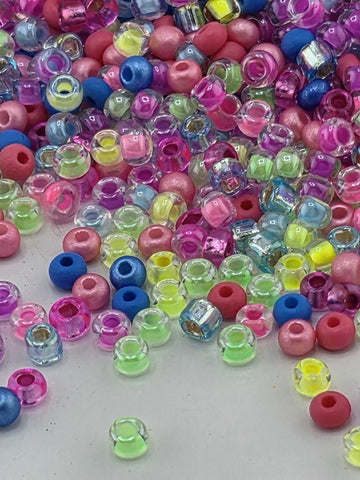 A colorful assortment of multicolored beads, including clear, blue, pink, and yellow beads, scattered across a surface.