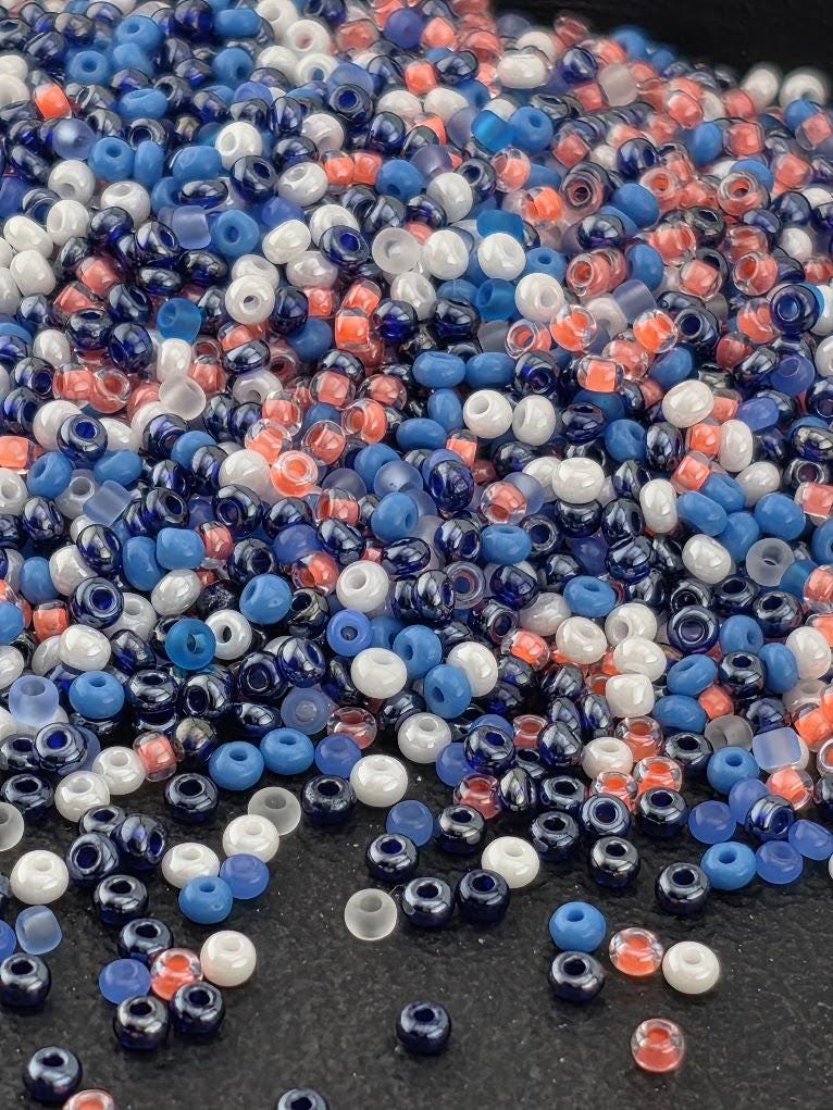 A pile of multicolored beads, including blue, white, and red, scattered on a dark surface.