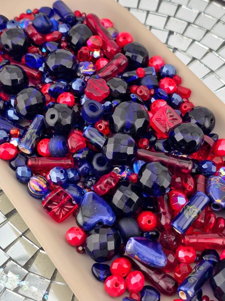 The image is a collection of various colorful beads, including red, blue, and black beads, arranged in a visually appealing manner.