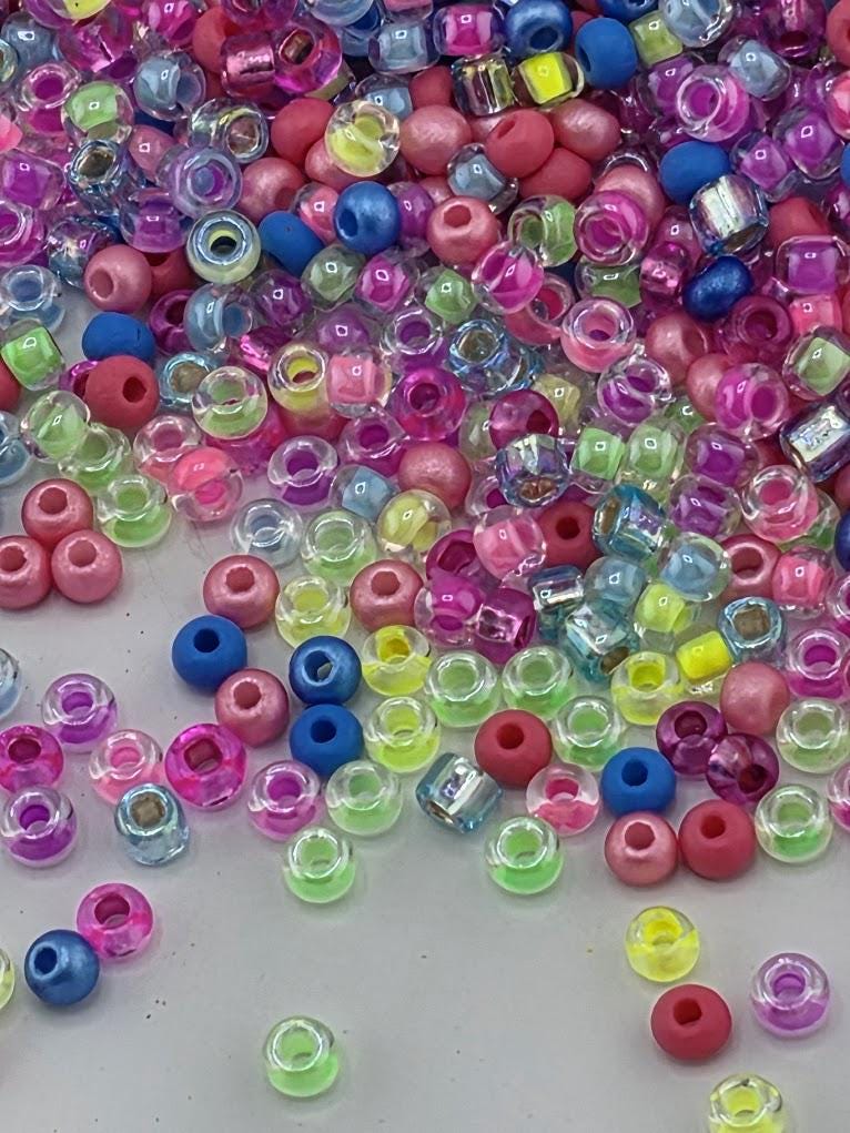 A colorful assortment of multicolored plastic beads, including clear, blue, pink, and yellow beads, scattered across a surface.