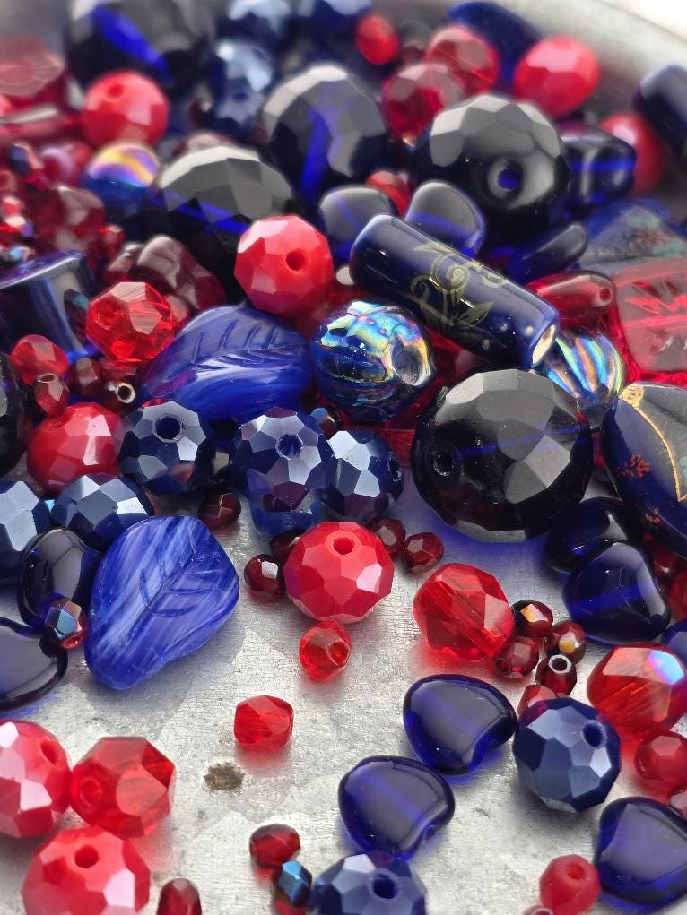 The image is a close-up of various colorful beads, including red, blue, and black beads, scattered together.