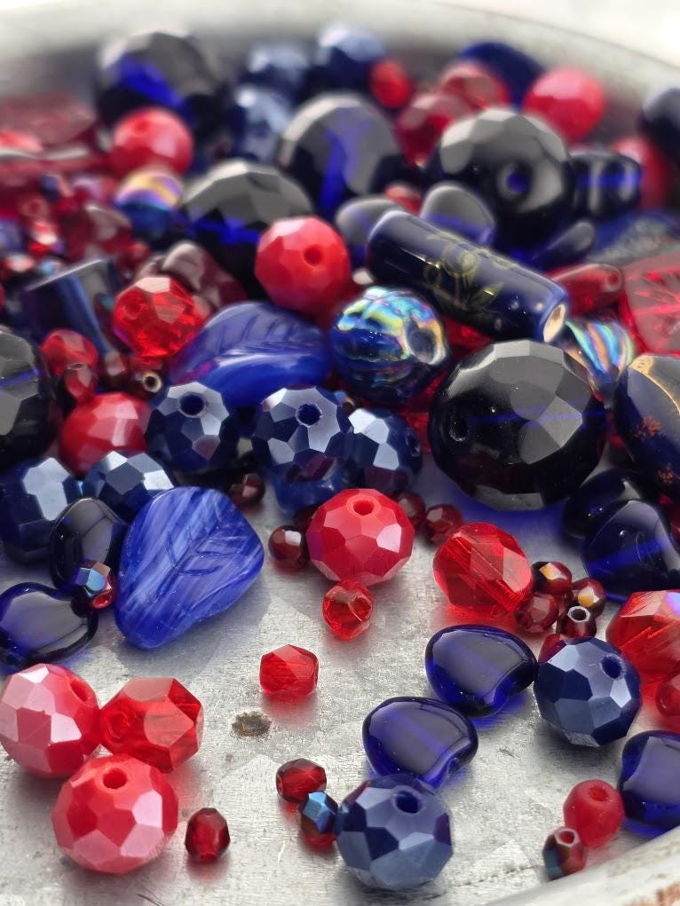 a collection of colorful glass beads, including red, blue, and black beads, scattered on a surface.