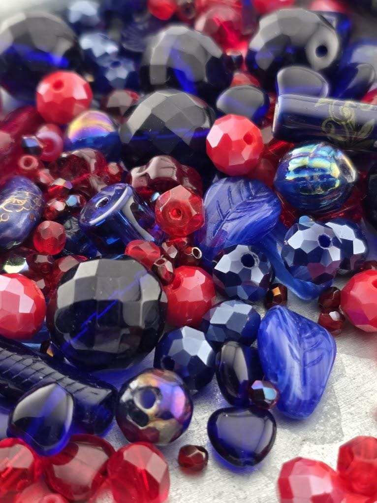 The image is a close-up of various colorful beads, including red, blue, and black beads, scattered together.