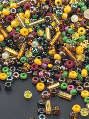 A colorful assortment of beads, including glass, metal, and plastic, scattered on a dark surface.