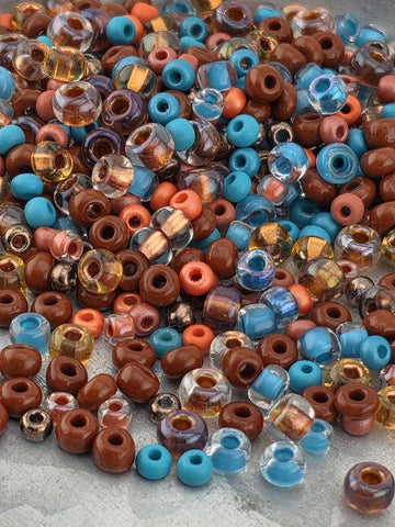 The image is a collection of various colored beads, including blue, brown, and clear beads, scattered on a surface.