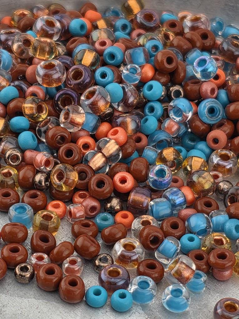 The image is a collection of various colored beads, including blue, brown, and orange, scattered together.