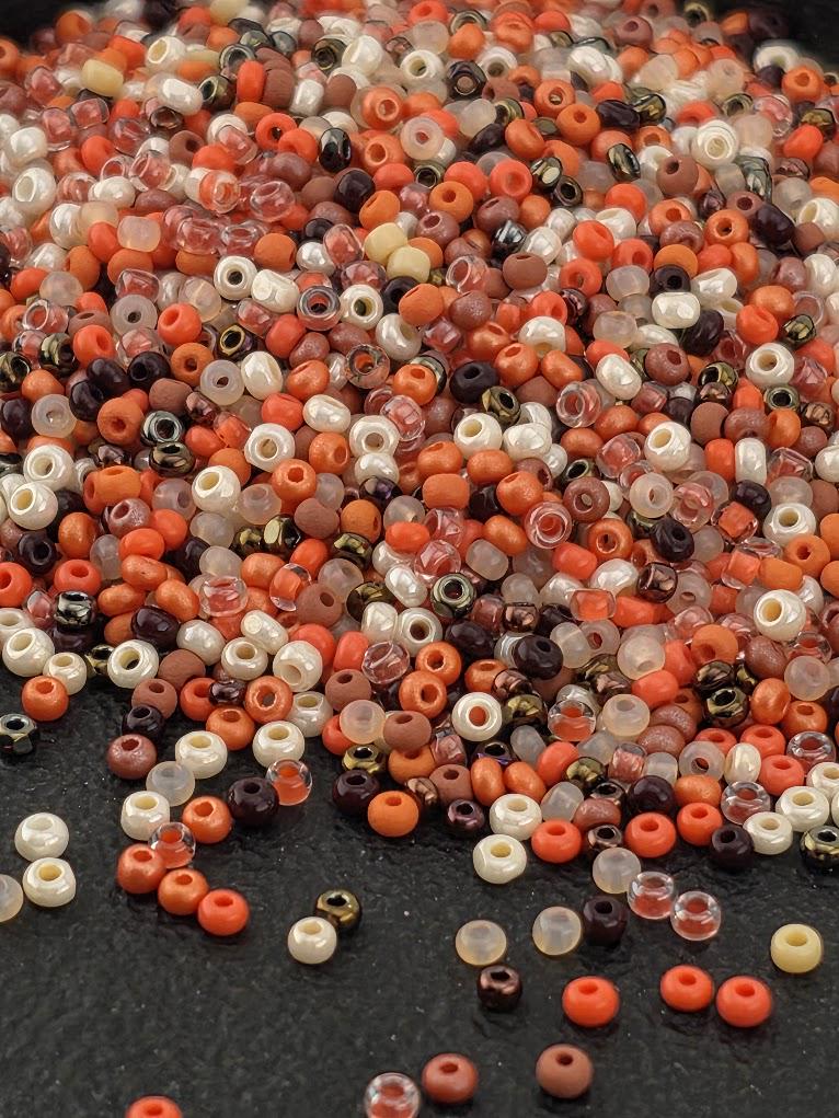 A large pile of various colored beads, including white, orange, and brown, scattered on a dark surface.