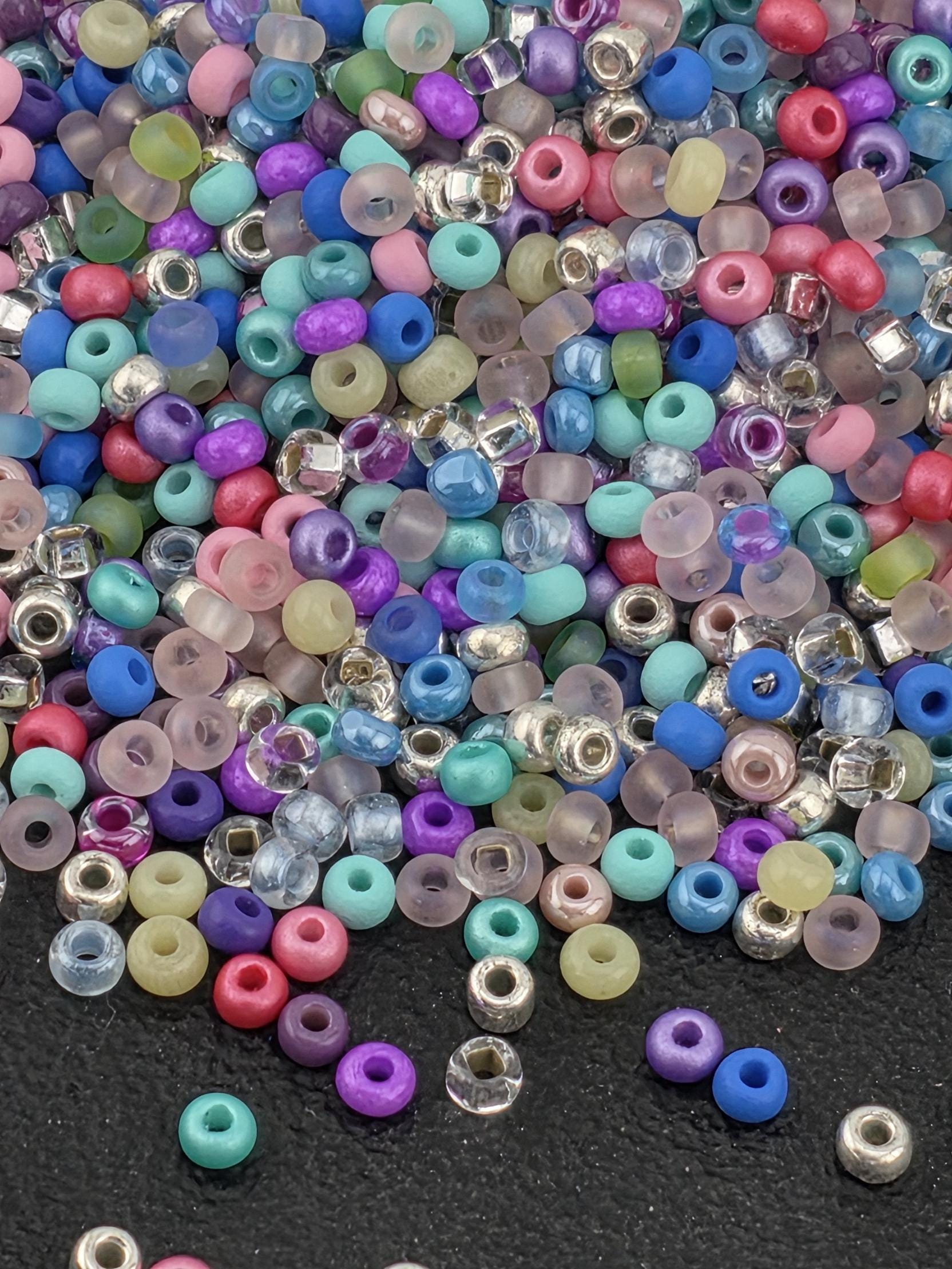 A colorful assortment of multicolored beads, including clear, transparent, and colored glass beads, scattered on a dark surface.