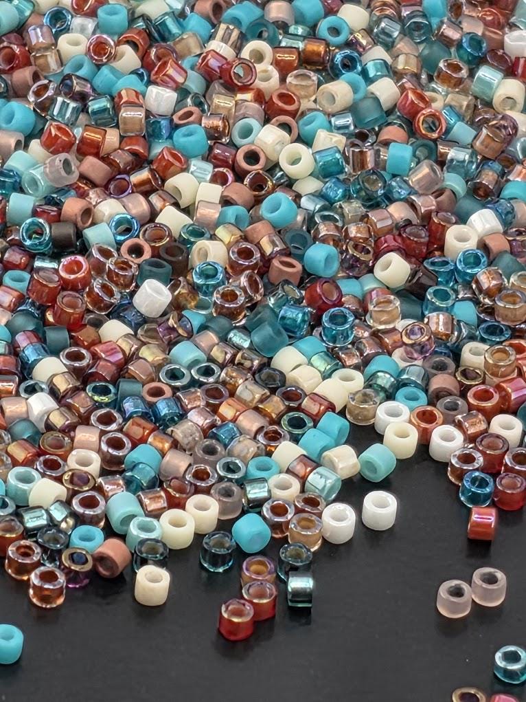 A colorful assortment of multicolored beads, including blue, red, white, and multicolored beads, scattered across a dark surface.