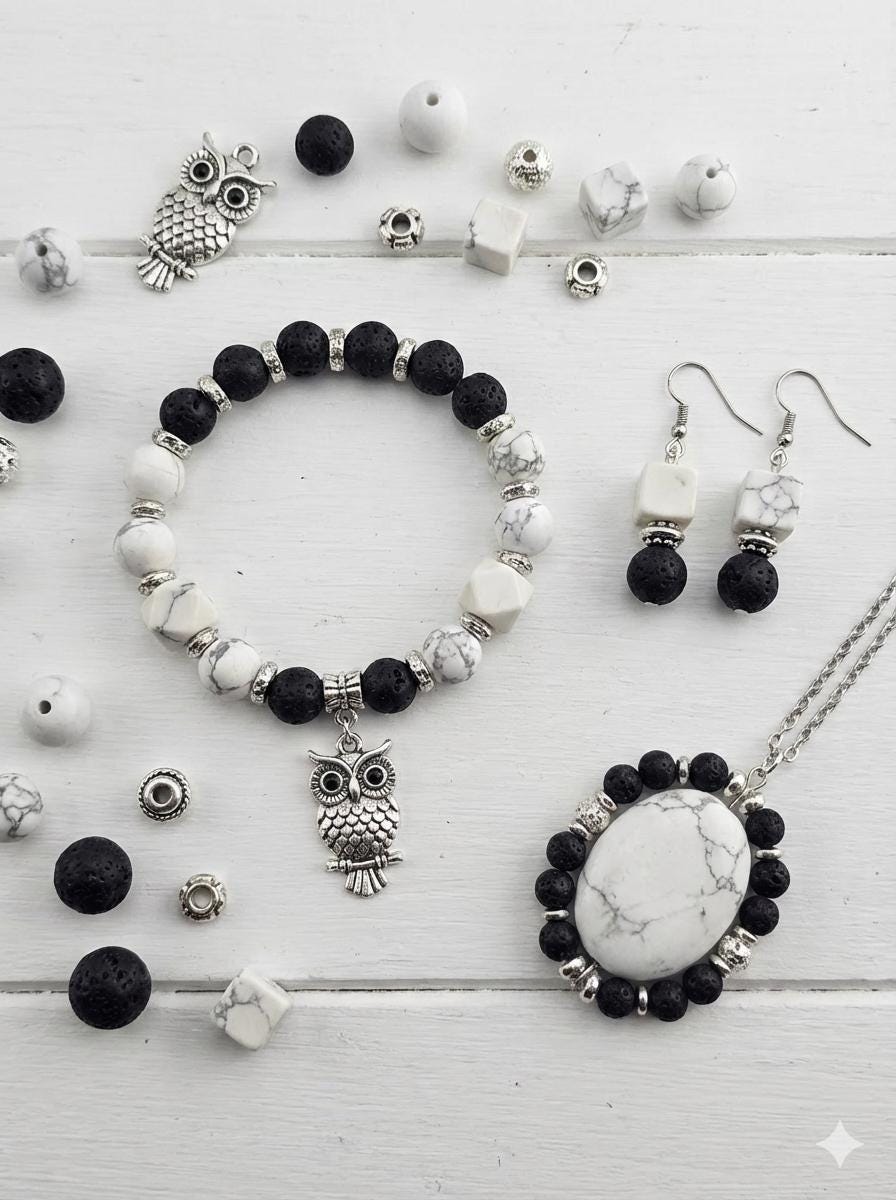 A collection of various beads, charms, and stones in shades of white, black, and silver, arranged on a surface.