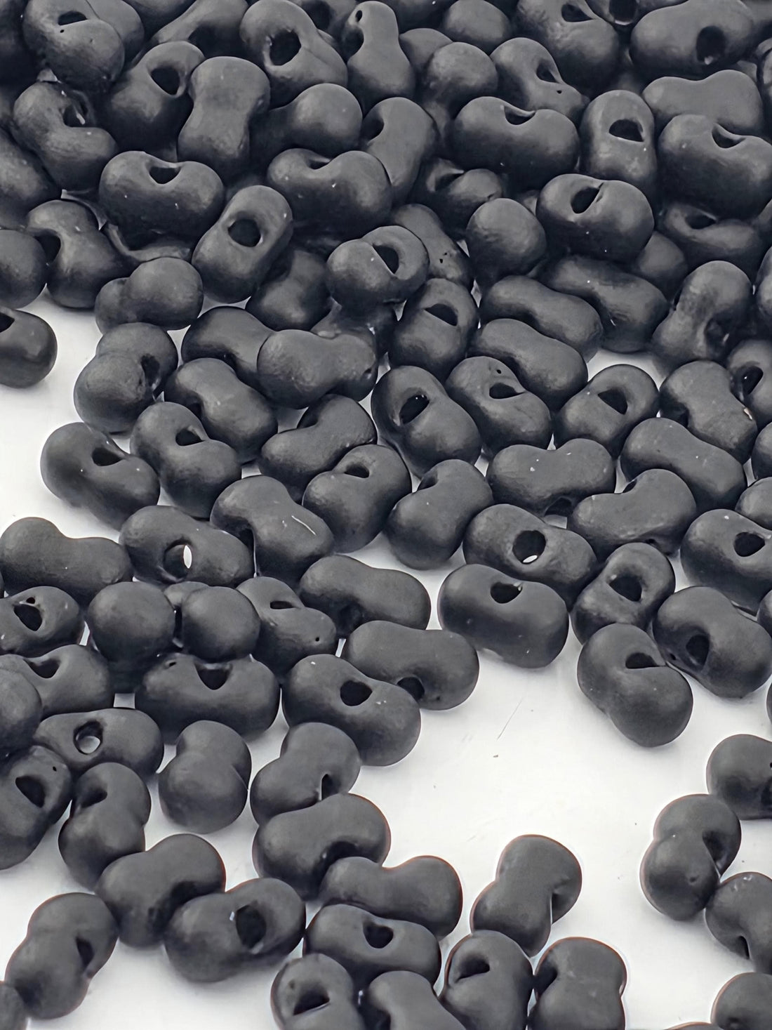 a collection of black beads or objects scattered on a white surface.