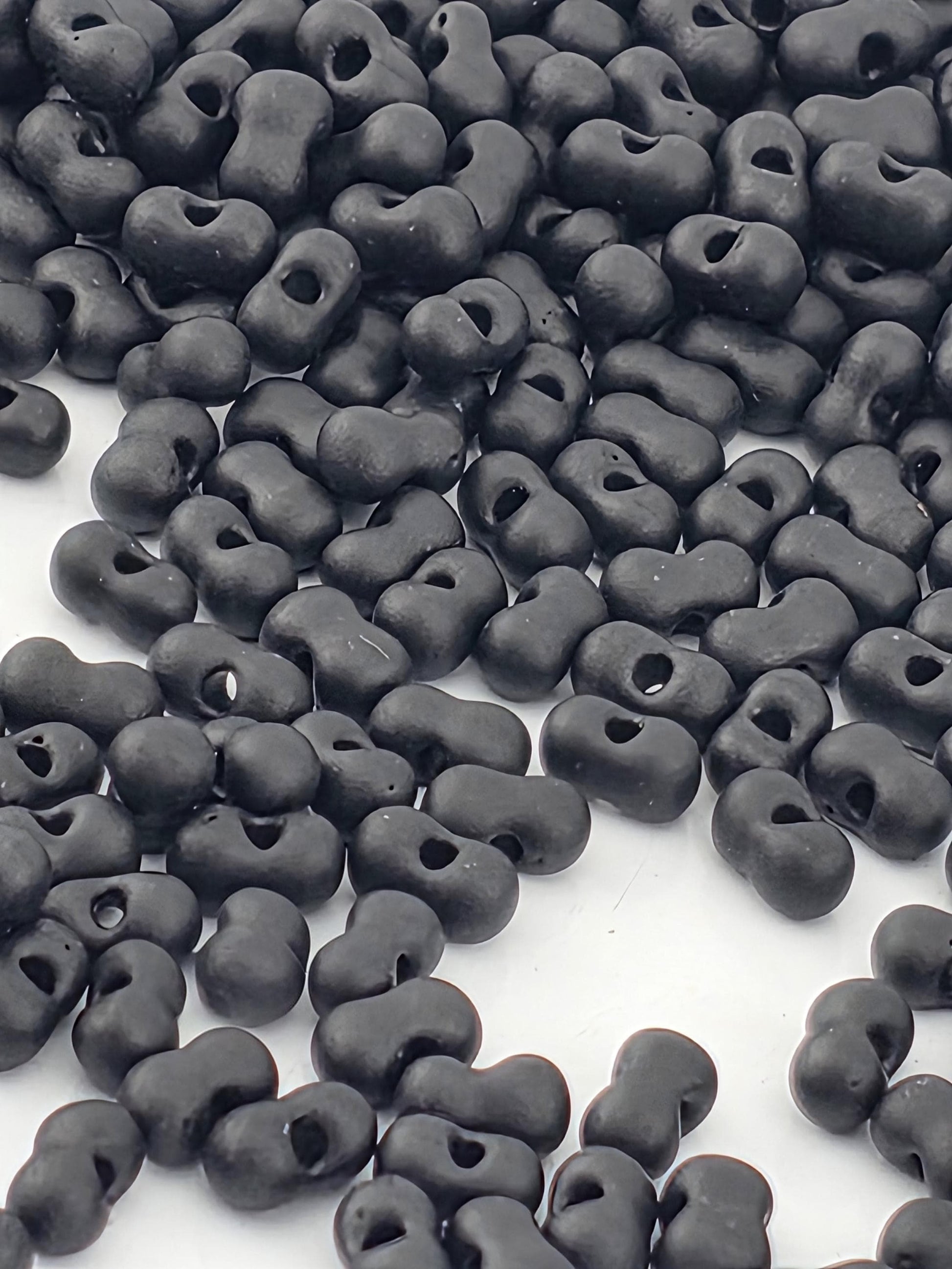 a large pile of black beads or objects scattered on a white surface.