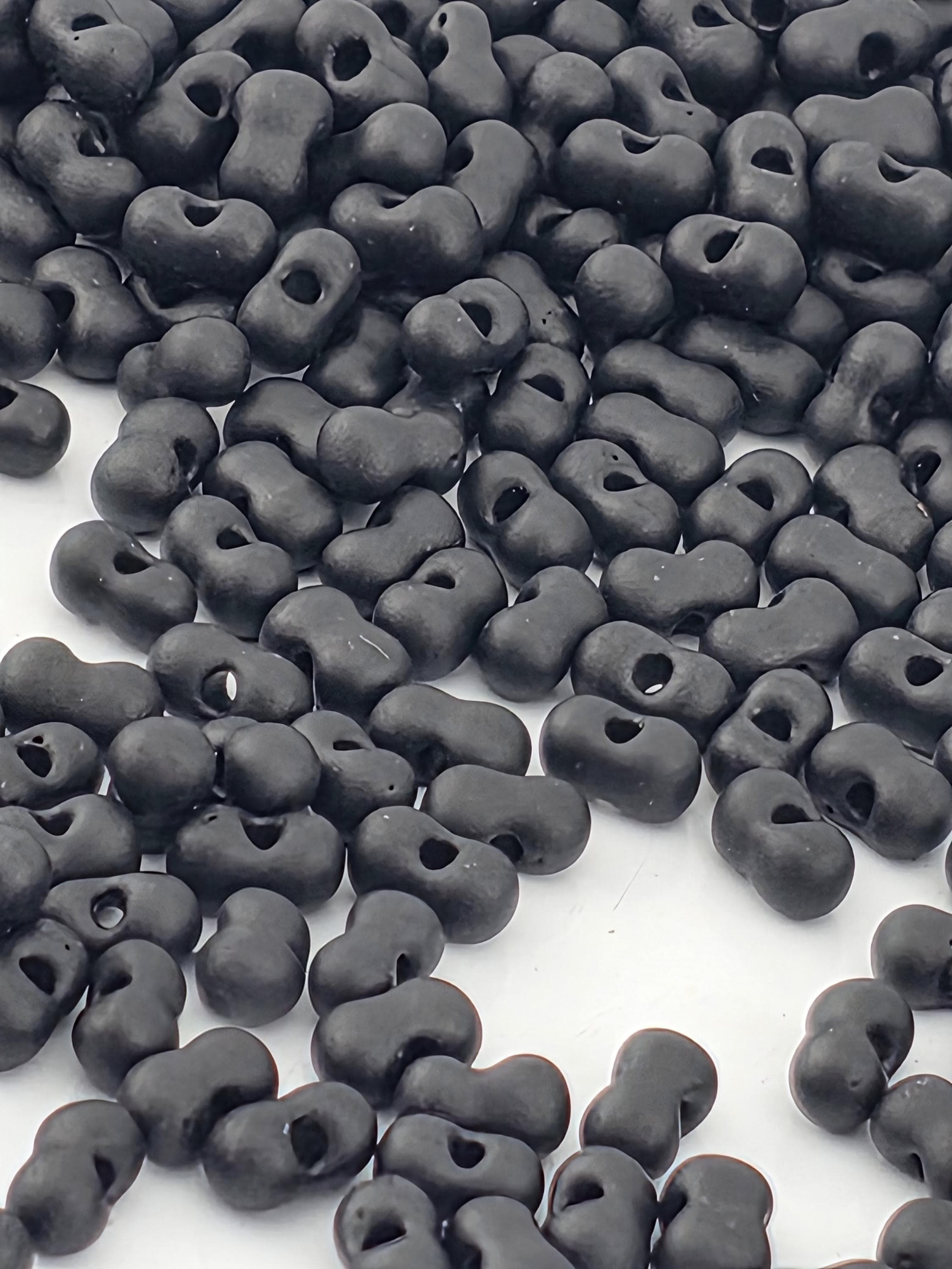 a large pile of black beads or objects scattered on a white surface.