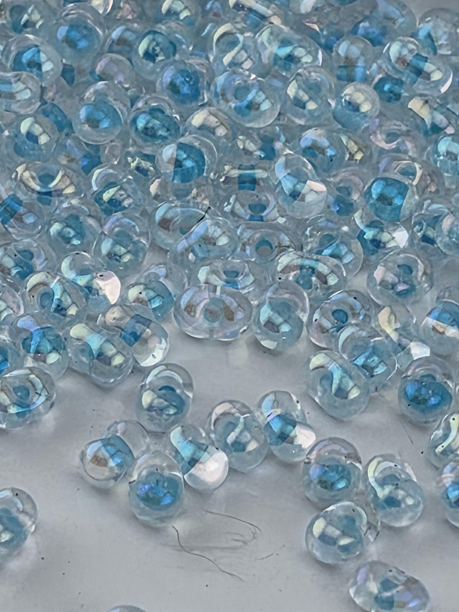 a close-up view of numerous clear, spherical objects with a blue tint, scattered across a surface.