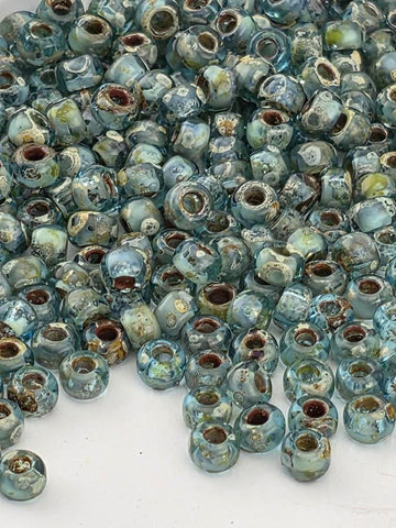 a large pile of small, blue glass beads scattered on a white surface.