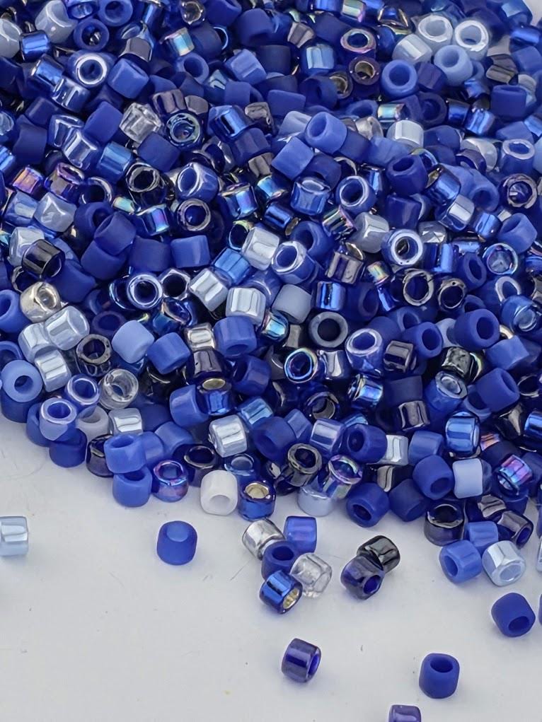A pile of blue and silver beads scattered on a white surface.