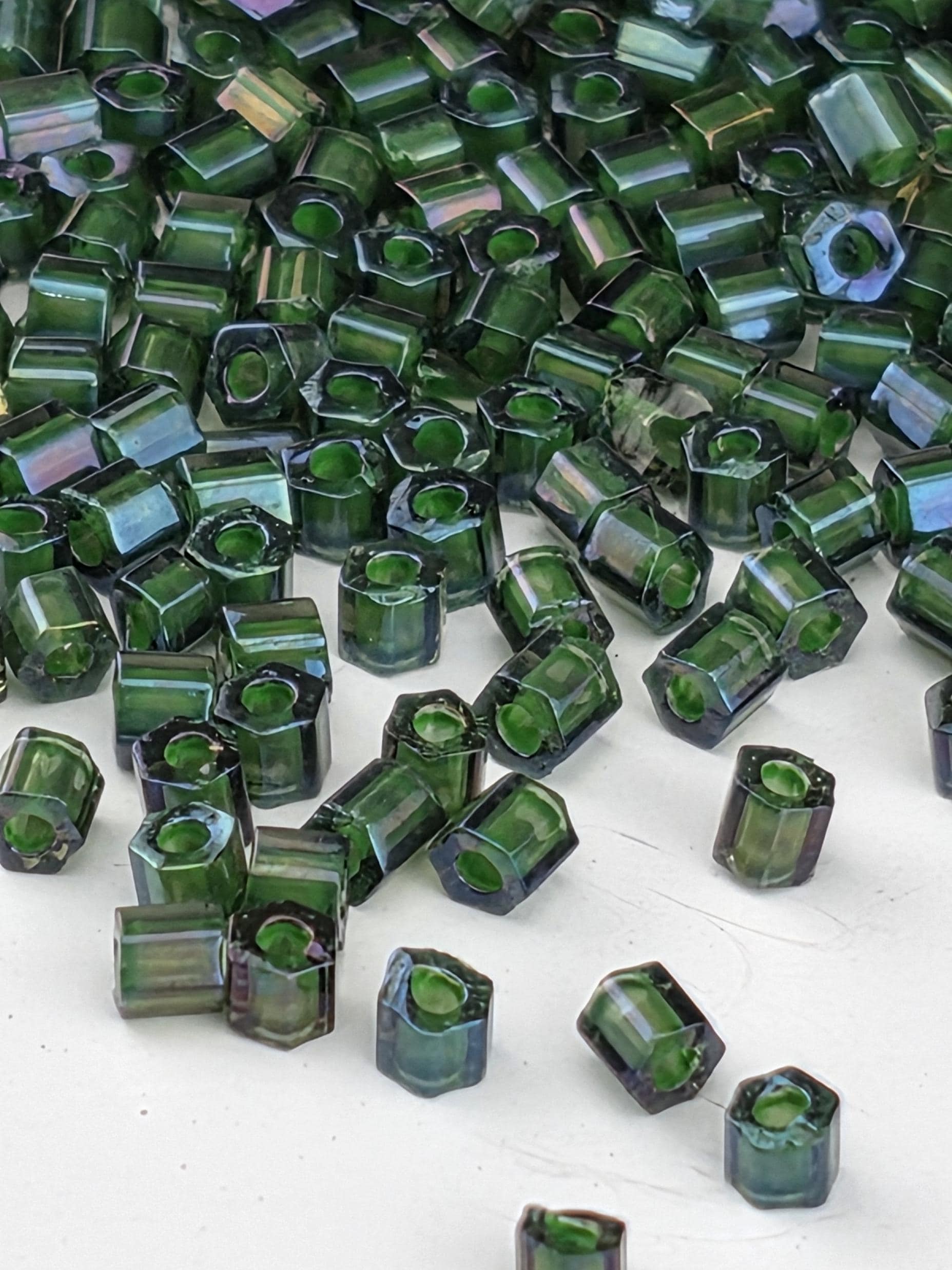 a collection of green glass beads scattered on a white surface.