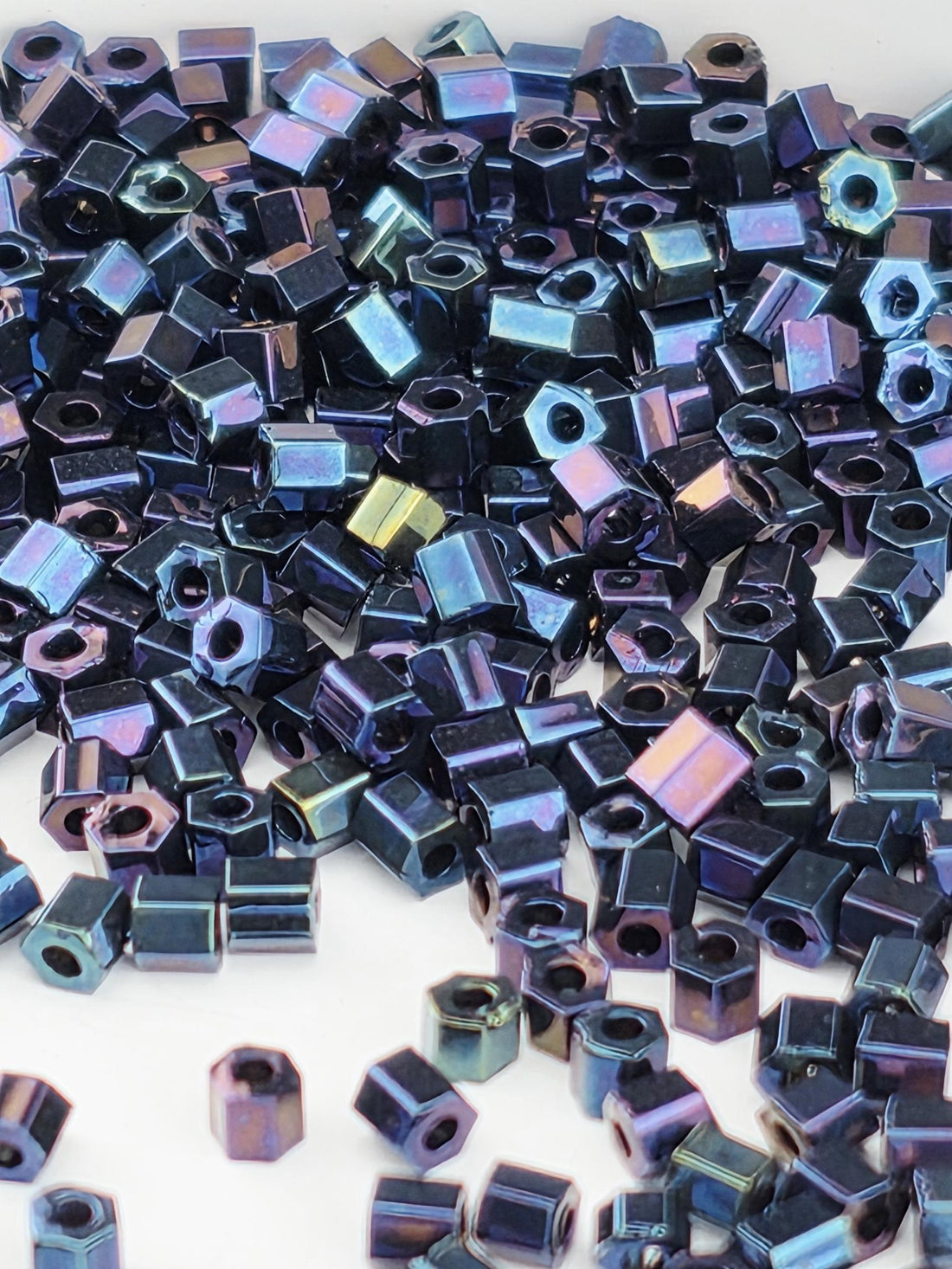 numerous small, metallic hexagonal objects in various shades of blue and purple, scattered across a white background.
